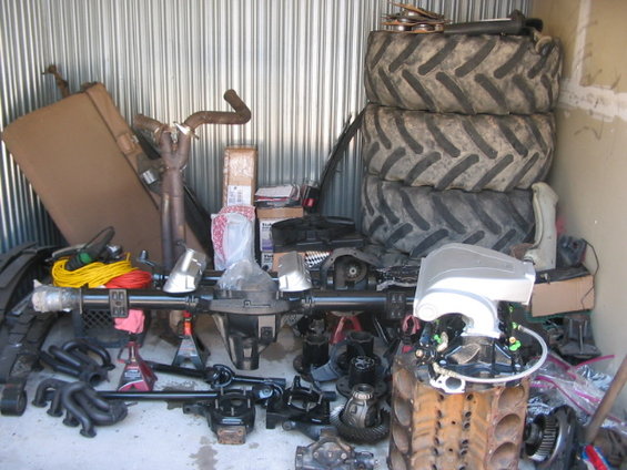 Vehicle parts: axles, exhaust, engine block, and stacked tires
