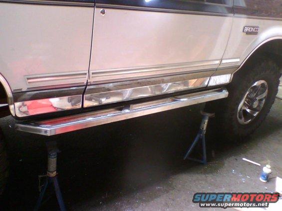 1993 Ford Bronco side view, silver body with chrome trim and running boards, on jack stands