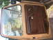 1978 Ford Bronco - The interior door panel of a vehicle shows brown trim and a side mirror visible through the window.