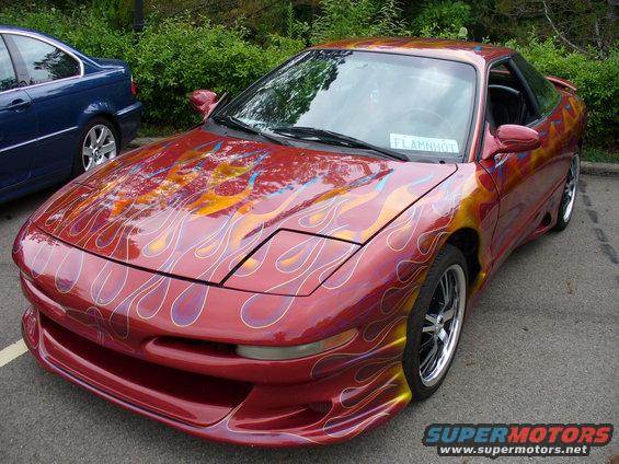 Red 1991 Ford Probe with flame decals and custom body kit, parked next to a blue car