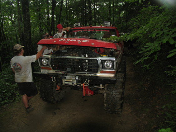 Red off-road truck with hood open and winch, "Lift it... Fat Chicks Can't Jump!!!" sticker on hood