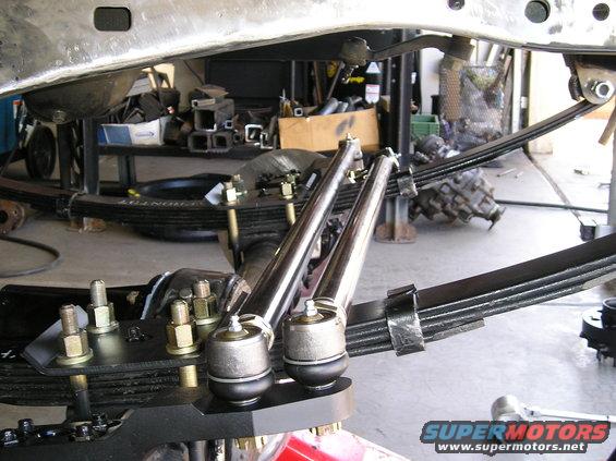 Close-up of new steering and suspension parts on a vehicle frame, with leaf springs visible
