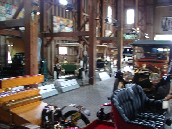 Interior view of a barn with several antique cars on display