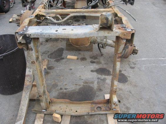 Rusty truck frame on wooden pallets, showing suspension components and differential