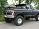1977 Ford F-150 - This lifted 1977 Ford F-150 pickup truck features a matte black finish with flame decals and a prominent hood scoop.