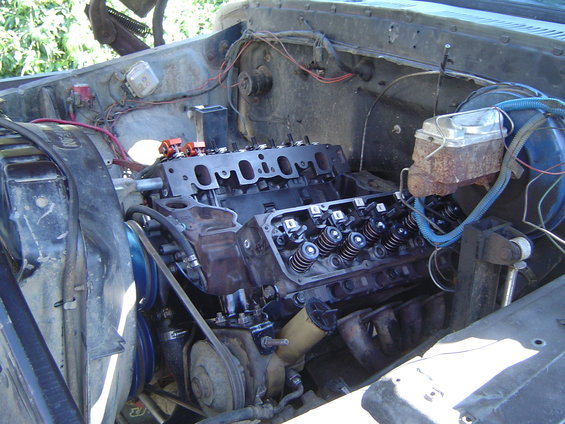 Engine bay with V8 engine disassembled, showing cylinder heads and intake manifold