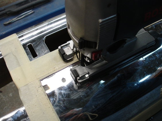 Jigsaw cutting into a chrome bumper, with masking tape applied