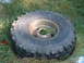 1994 Jeep YJ - A weathered off-road tire and rim rests in overgrown grass, showing signs of age and disuse.