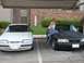 1991 Ford Mustang - A woman sits on the hood of a black 1991 Ford Mustang, parked next to a white Mustang.