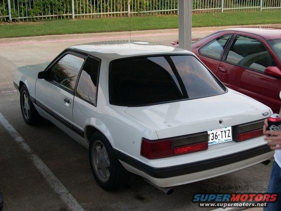 White 1991 Ford Mustang coupe parked next to a red car, rear view