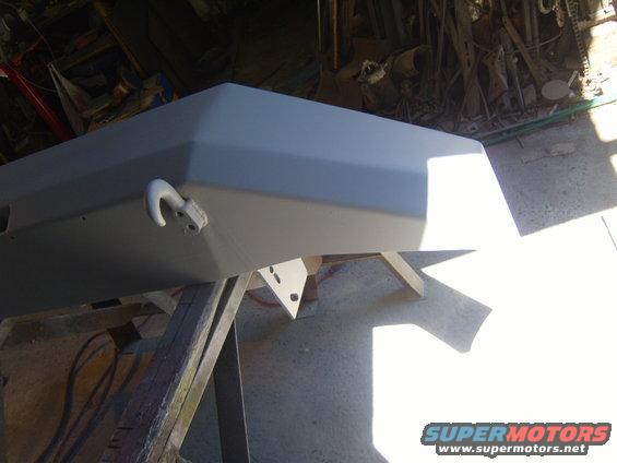 Gray primer front bumper with tow hook, supported by wooden sawhorses