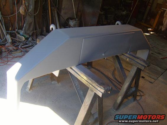 Primer-coated front bumper on sawhorses in a workshop
