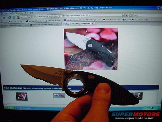 Gerber folding knife held up to a computer screen showing a picture of another Gerber knife