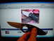 1989 BMW 3 Series - A hand holds a Gerber folding knife in front of a computer displaying an eBay listing for similar knives.