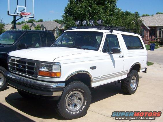 White 1994 Ford Bronco parked in driveway next to a black truck