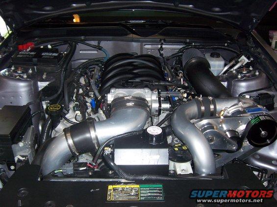 Engine bay with a supercharger, intake, and V8 engine components visible