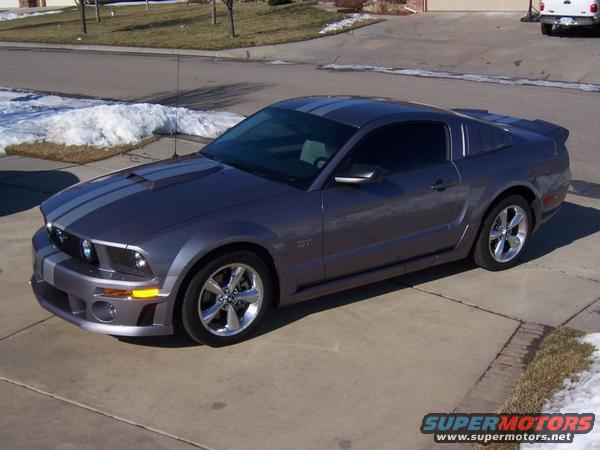 Gray Ford Mustang GT coupe with silver racing stripes, parked on a concrete driveway