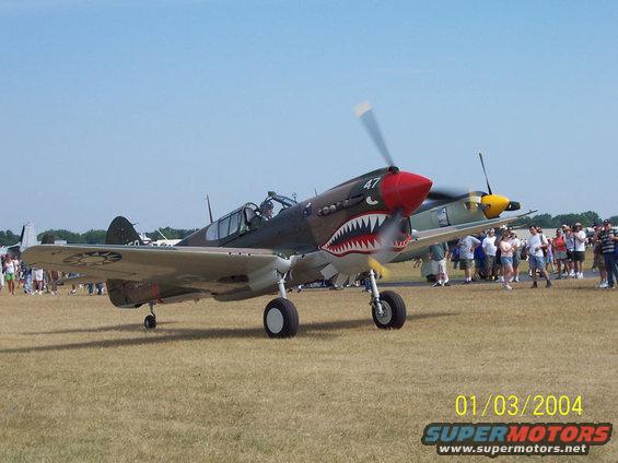 Fighter plane with shark teeth nose art and number 47 on propeller spinner