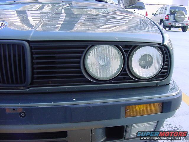 1989 BMW 3 Series front grille and dual headlights. Another SUV is parked behind