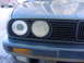 1989 BMW 3 Series - Close-up of the front grille and headlights of a car, with another vehicle in the background.