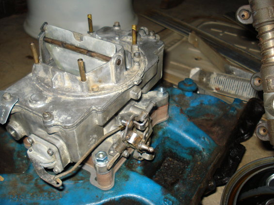 Close-up of a carburetor mounted on a blue engine block