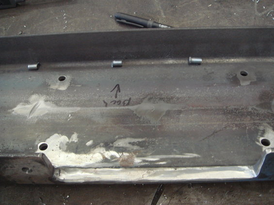 Metal part with four bolts and handwritten text 'Back' with an arrow