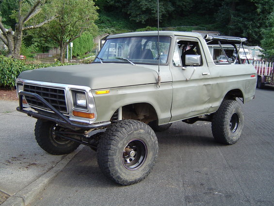 1978 Ford Bronco with lifted suspension and aftermarket front bumper, parked on a street