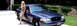1998 Ford Crown Victoria - A woman poses next to a blue 1998 Ford Crown Victoria parked in a driveway.