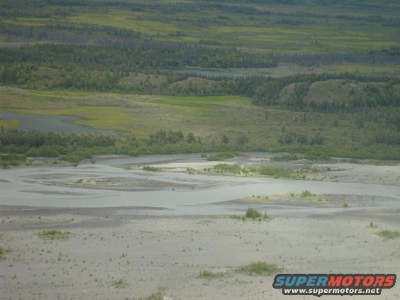 wide view of a river delta with green hills and trees in the background