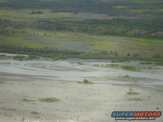 Wide river delta with sandy banks and green vegetation under a hazy sky