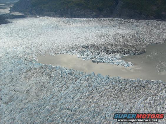 Aerial view of a large glacier with a body of water at its edge