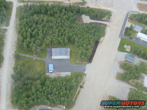Aerial shot of a building complex surrounded by trees and dirt roads