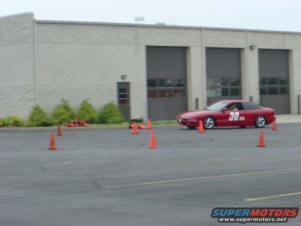 Red 1997 Ford Probe with racing number 30 on the door, driving on a track with orange cones