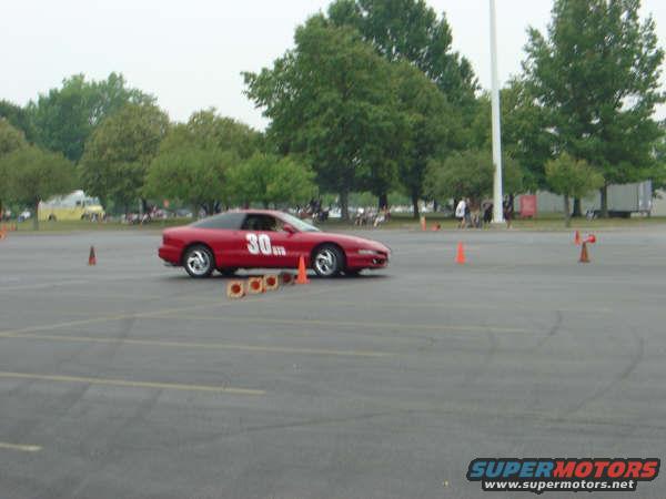 1997 Ford Probe in red with number 30 on the door, driving on a track with orange cones