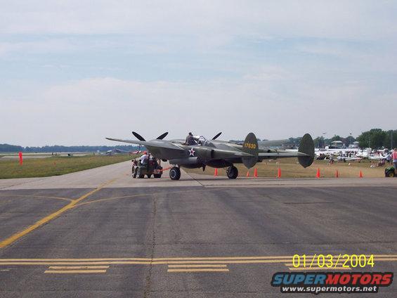 Lockheed P-38 Lightning airplane on tarmac with a tow vehicle attached
