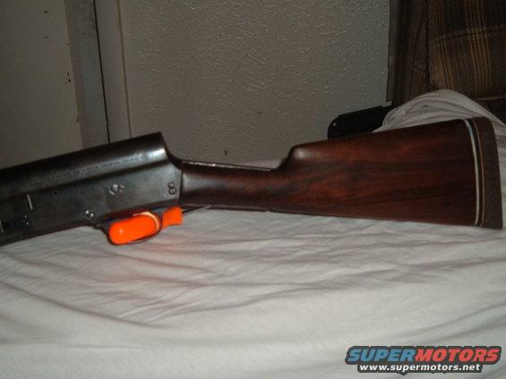 Wooden shotgun stock and metal receiver with an orange safety device