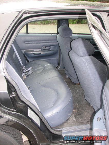 Black leather rear seats and door panel of a car. A sticker is visible on the door jamb