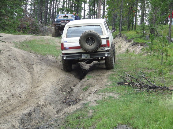 White 1990 Ford Bronco rear view, off-roading with another vehicle behind