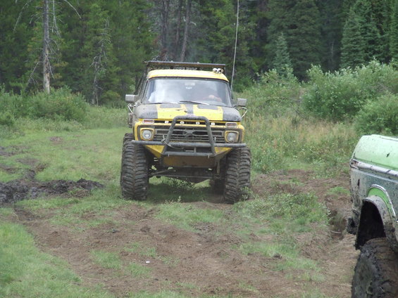 Yellow Ford F-Series truck with off-road tires on a muddy trail