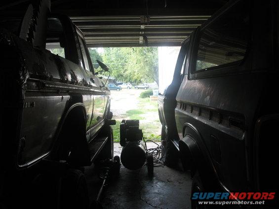 Two 1978 Ford Broncos in a garage, viewed from the side, with one slightly in front of the other