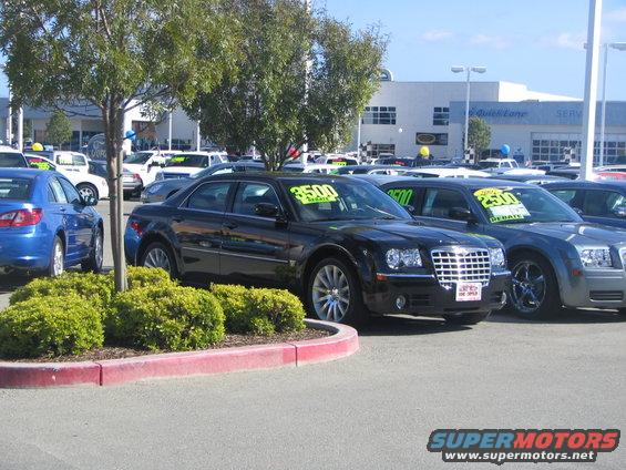 Black Chrysler 300 sedan with $3500 price tag on windshield, parked at dealership