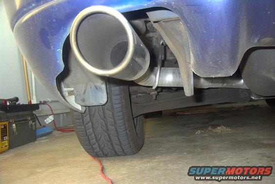 Close-up of a car's exhaust pipe and rear tire