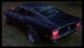 1968 Ford Mustang - This matte black 1969 Ford Mustang fastback is viewed from the rear three-quarter angle, parked on grass.
