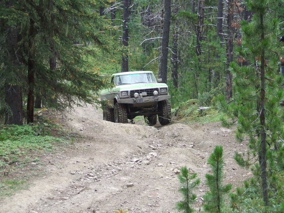 Light green off-road truck with aftermarket bumper and winch on a dirt trail