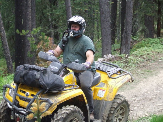 Yellow ATV with rider in helmet on a dirt trail
