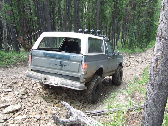 Rear view of a 1990 Ford Bronco on a rocky forest trail