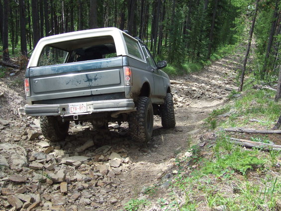 Rear view of a 1990 Ford Bronco on a rocky forest trail