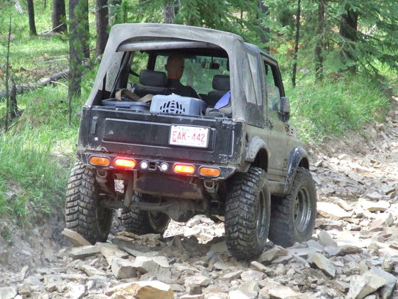 Off-road Suzuki Samurai on a rocky trail, rear view. Driver visible