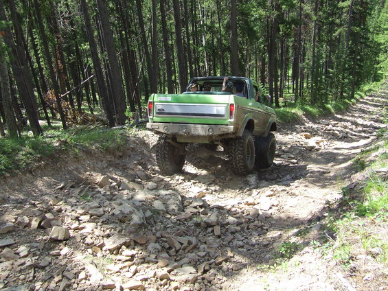 Green off-road truck with large tires on a rocky trail