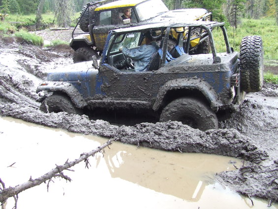 Blue off-road vehicle stuck in mud with another vehicle behind it